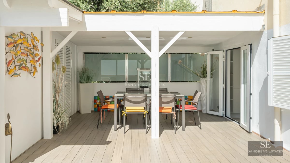 Large swimming pool lined with sun loungers, with a modern house with minimalist design in the background and lush vegetation.