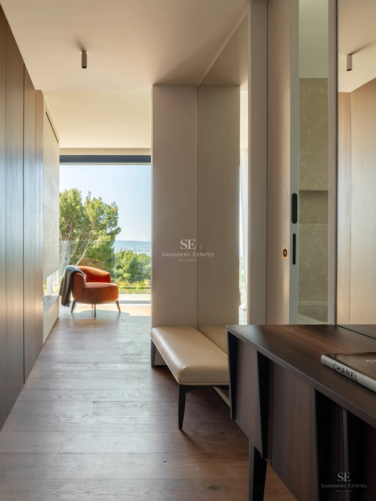 Spacious living room with floor-to-ceiling sea view windows, light wood floors, and minimalist design. Panoramic views and abundant natural light.