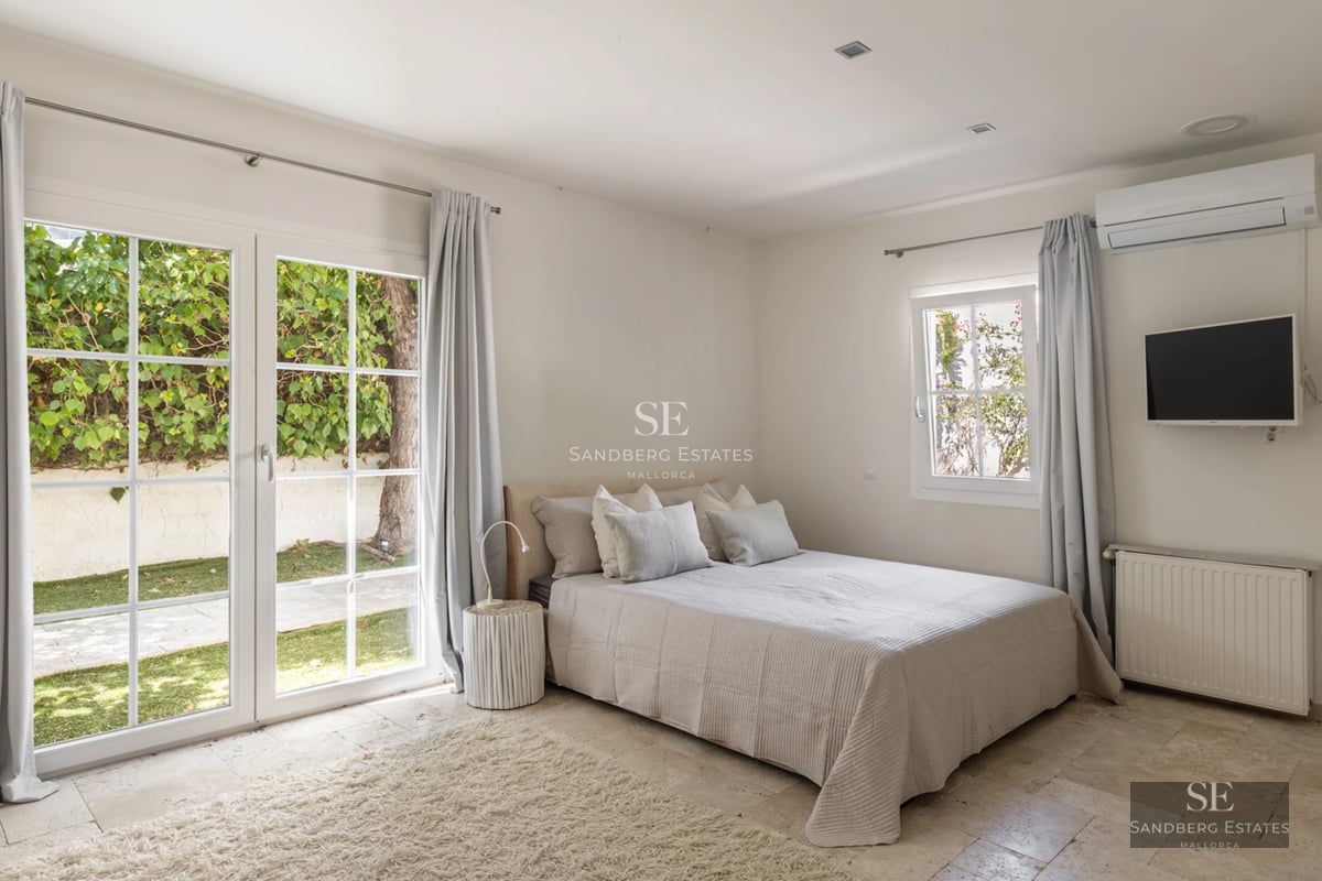 Spacious living room with floor-to-ceiling windows, light wood flooring, modern fireplace and minimalist furniture. Panoramic sea views. Bright and elegant.