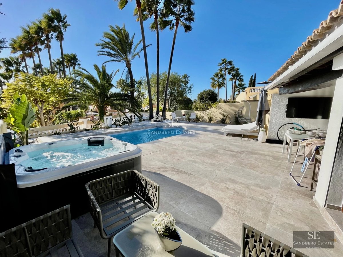 Aerial view of a luxurious villa with infinity pool, wooden terrace, and lush garden. Modern and minimalist design.