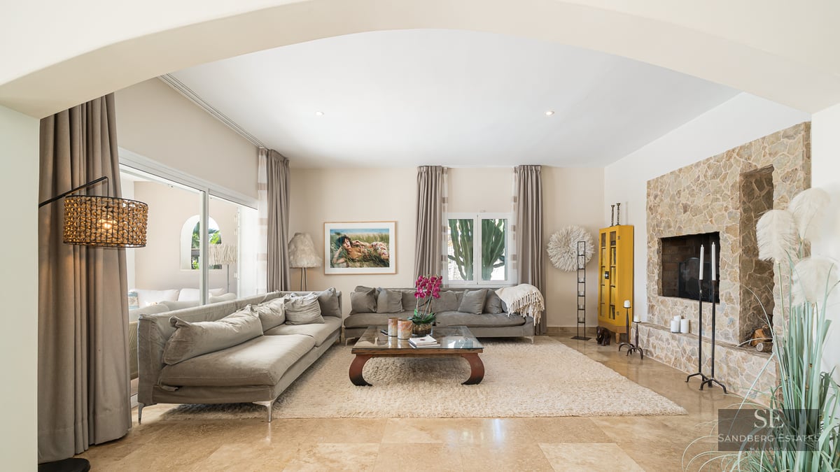 Spacious living room featuring grey sofas, a beige rug, and a large natural stone fireplace wall.