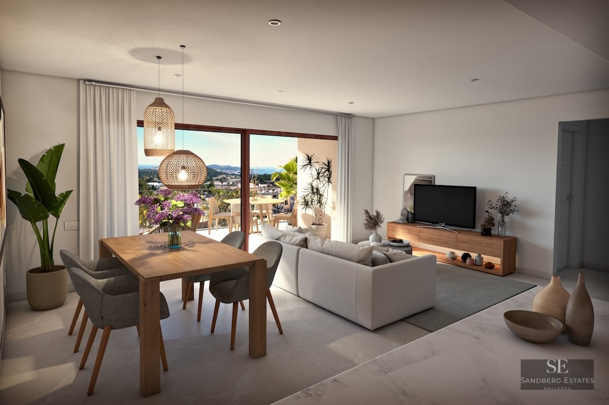 Bright open living room with a grey sofa, wooden dining table, and large glass doors opening to a scenic balcony view.