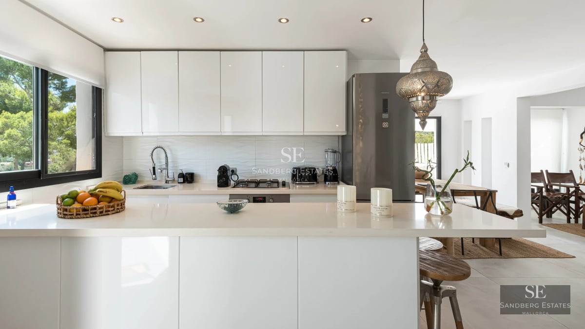 Spacious living room with floor-to-ceiling windows, gray sofa, modern coffee table, and light wood flooring. Abundant natural light.