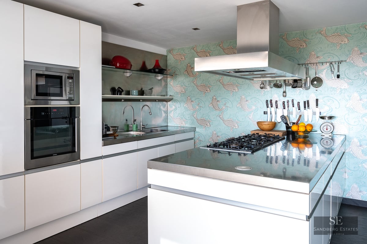 Contemporary kitchen with white cabinets, stainless steel countertops, and a unique blue koi fish wallpaper.
