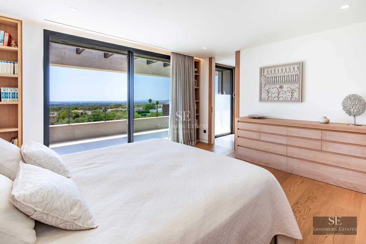 Spacious living room with floor-to-ceiling windows, modern sofas, designer rug and fireplace. View of garden with pool. Abundant natural light.