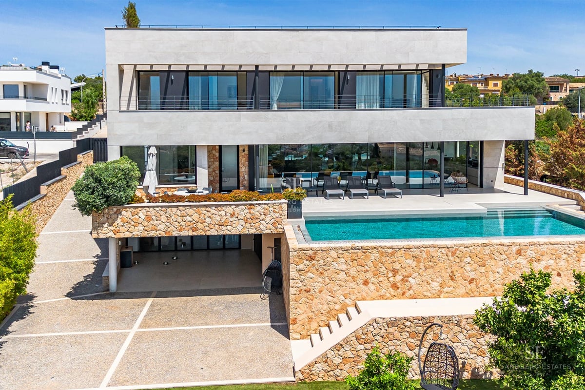 Exterior of modern house with infinity pool, lush garden, and minimalist architecture. Large windows and sunny terrace.