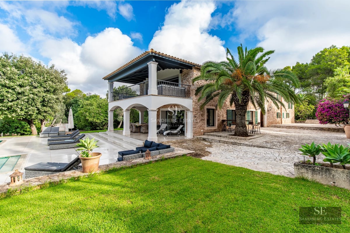 View of a modern infinity pool, surrounded by lush vegetation with a minimalist design house in the background.