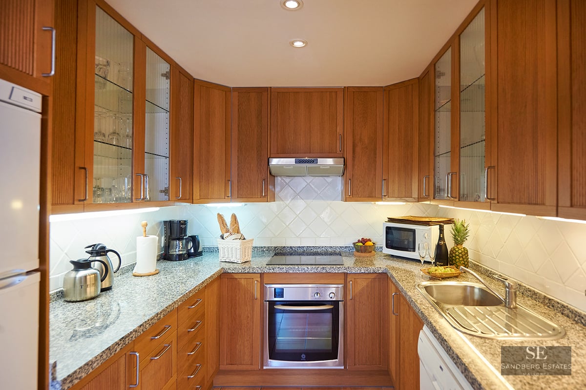 Classic U-shaped kitchen featuring wood cabinets, grey granite countertops, and integrated stainless steel appliances.