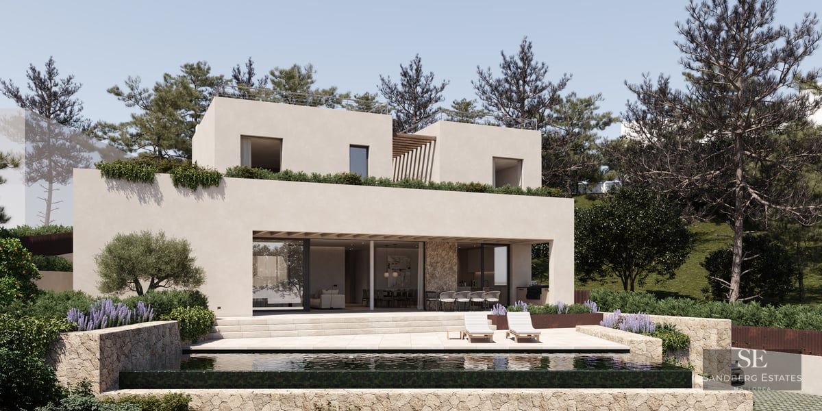 A modern two-story beige villa with an infinity pool, stone walls, and sun loungers under a clear sky.