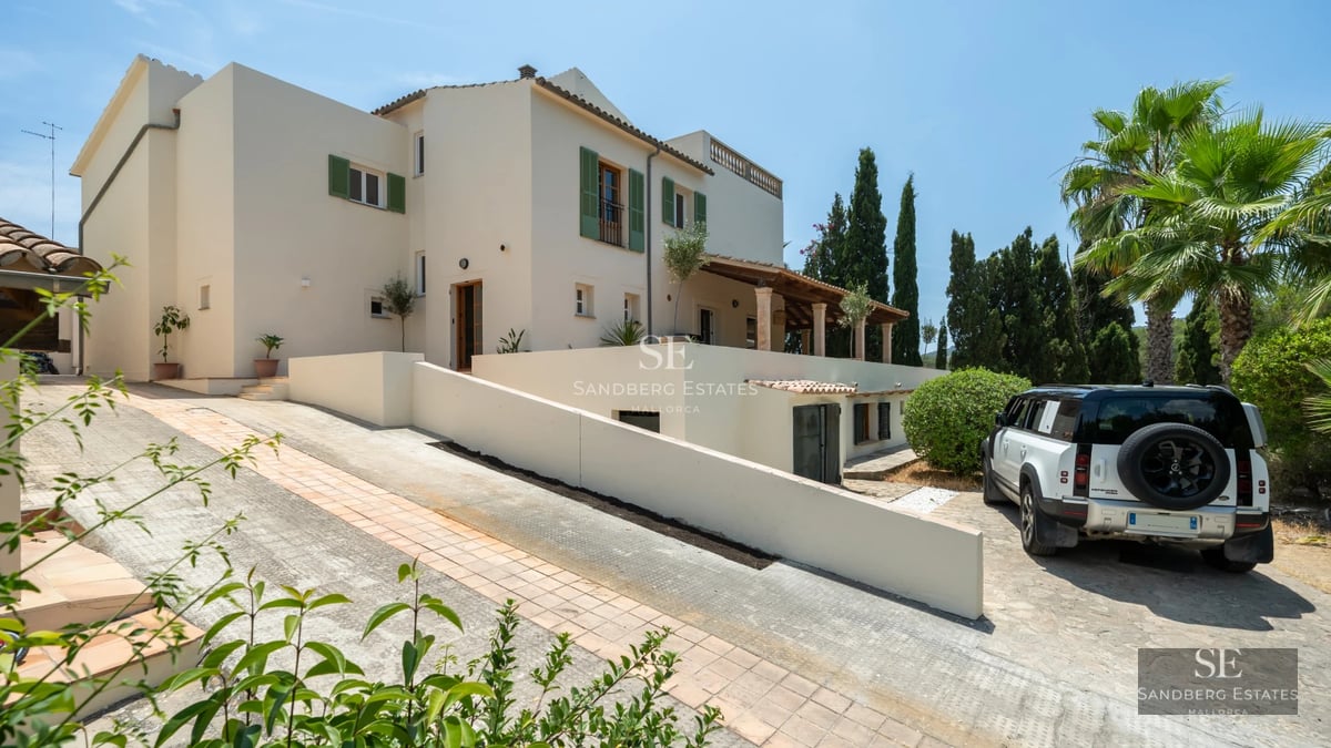 View of a modern pool with stylish loungers, surrounded by a green garden and a two-story minimalist house.