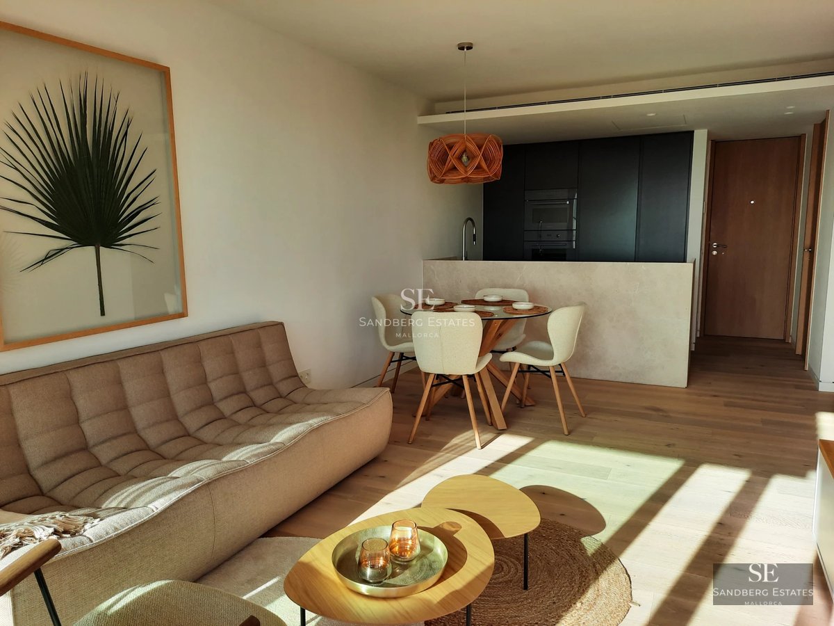 View of a blue infinity pool with white sun loungers, surrounded by greenery. Modern and elegant design.