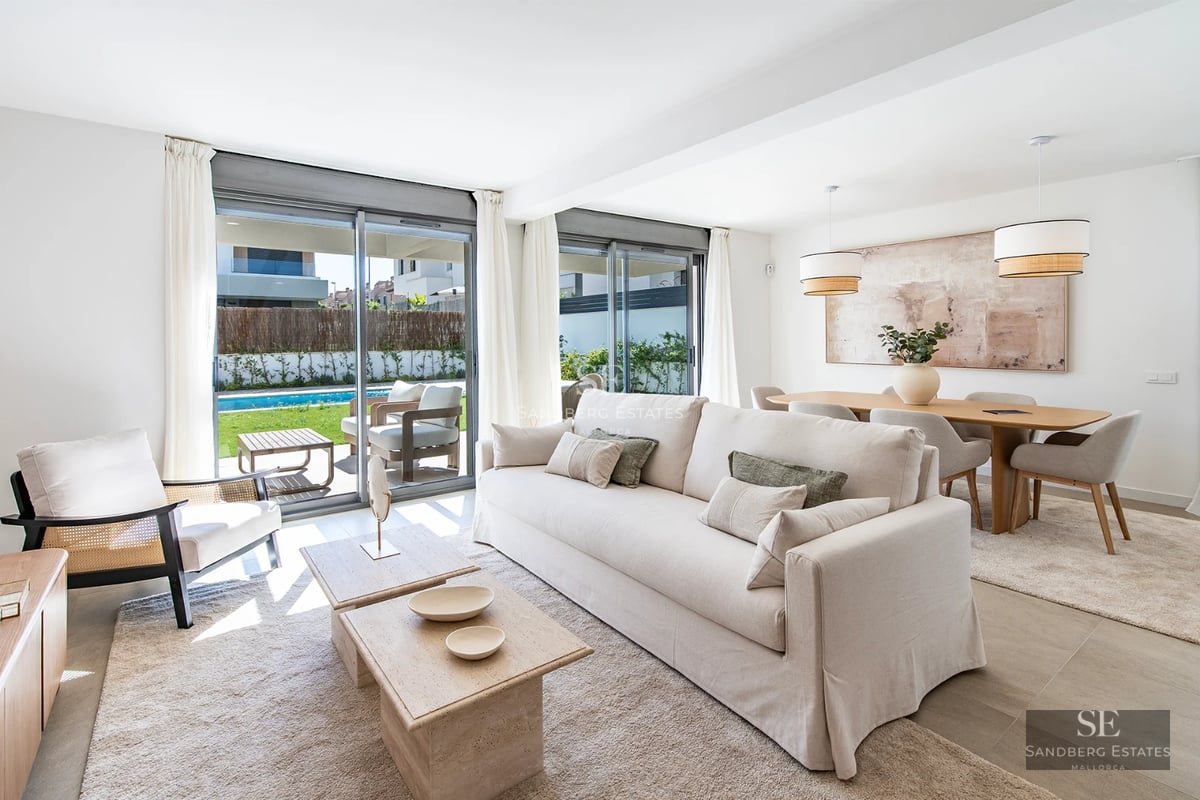Large, reflective pool surrounded by minimalist terrace. Modern design, natural light, immaculate lawn and bright blue sky.
