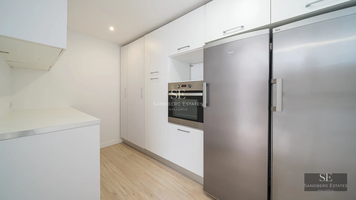 Spacious balcony with sea view, wood flooring, glass railing, modern furniture. Natural lighting and minimalist design.