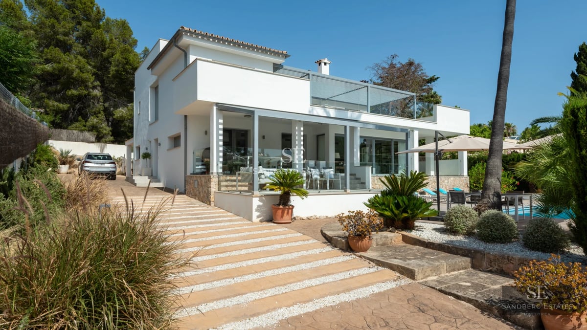 Exterior of a modern villa featuring an infinity pool, spacious terraces, and lush garden. Minimalist architecture, panoramic windows, and landscaping.