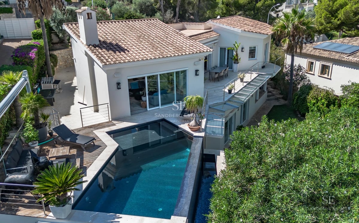 Spacious terrace with infinity pool and sea view. Modern furniture, glass railing and minimalist design.