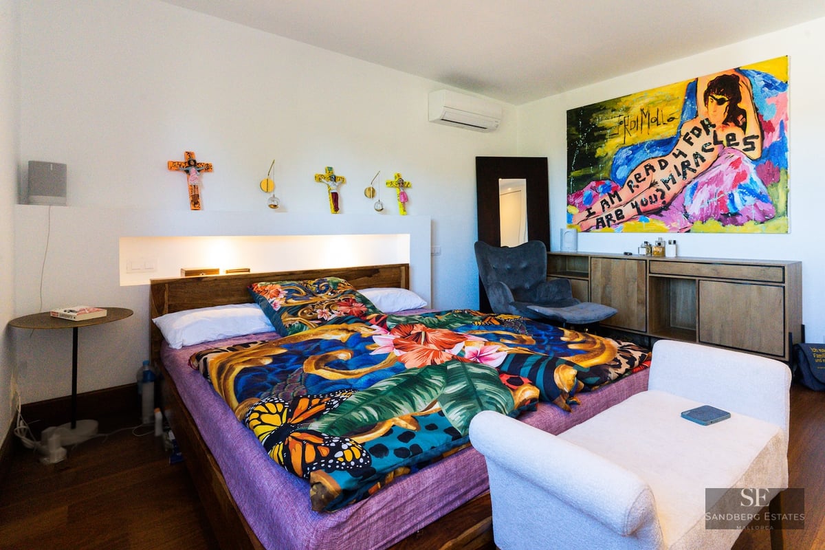 Bright bedroom featuring a bed with colorful floral bedding, large modern artwork, and warm recessed lighting.
