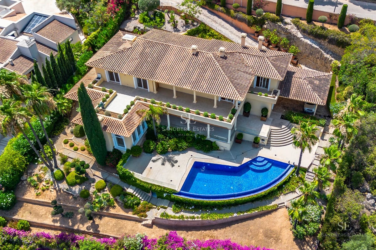 Exterior view of a modern villa featuring an infinity pool, large windows, and minimalist architecture. Lush garden and clear skies.