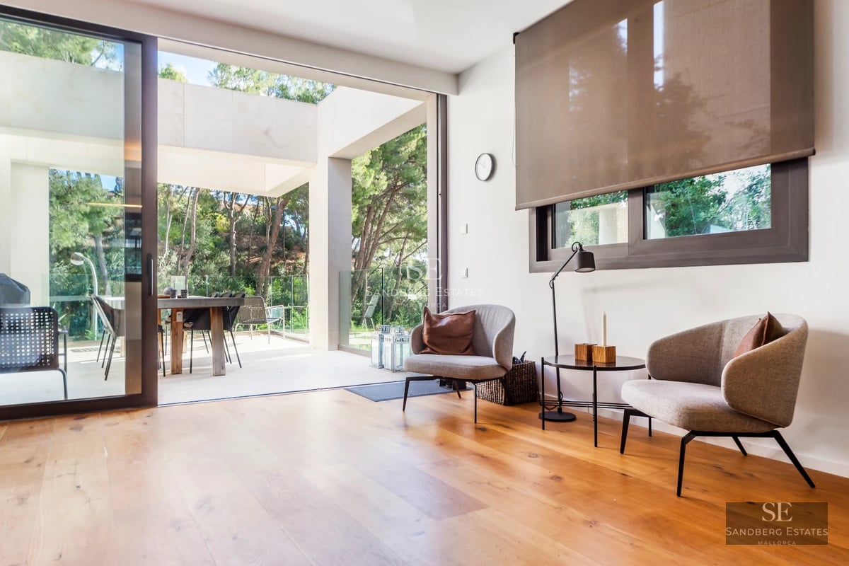 Exterior view of a modern villa featuring an infinity pool, lush garden, and spacious terraces. Contemporary architecture and manicured landscaping.