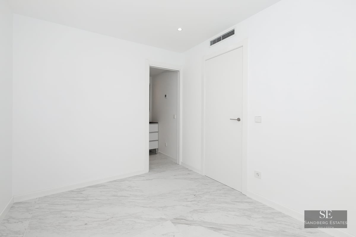 Bright empty room with white walls, polished grey-veined marble floors, and modern white doors.