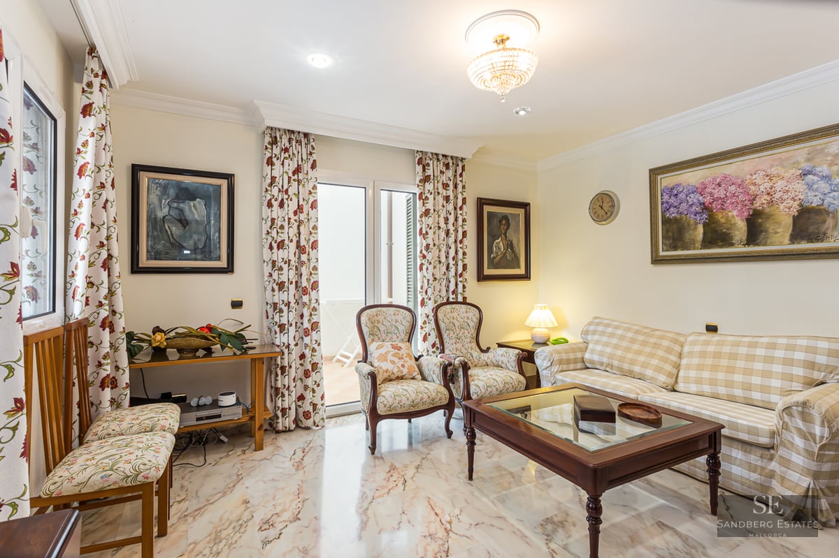 Living room featuring a plaid sofa, floral armchairs, wooden coffee table, and polished marble flooring.