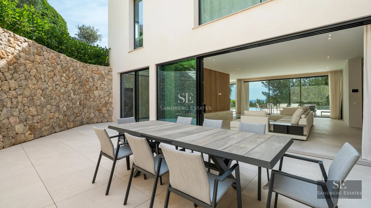 Spacious living room with panoramic sea view windows, light wood flooring, modern furniture and elegant lighting.