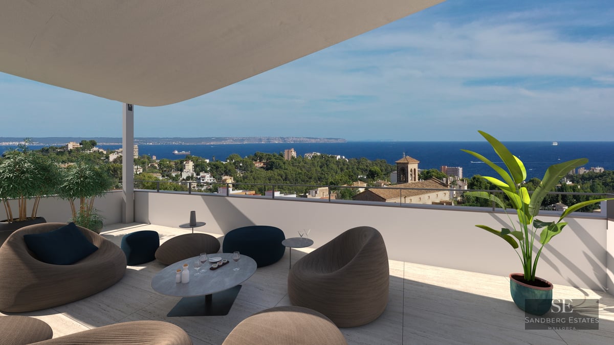 Modern rooftop terrace with designer lounge seating overlooking a Mediterranean coastal city and the blue sea.