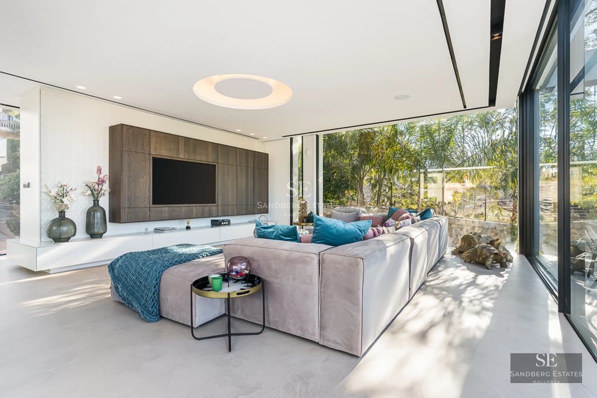 Spacious living room with picture windows, light wood floors, minimalist decor. Abundant natural lighting.