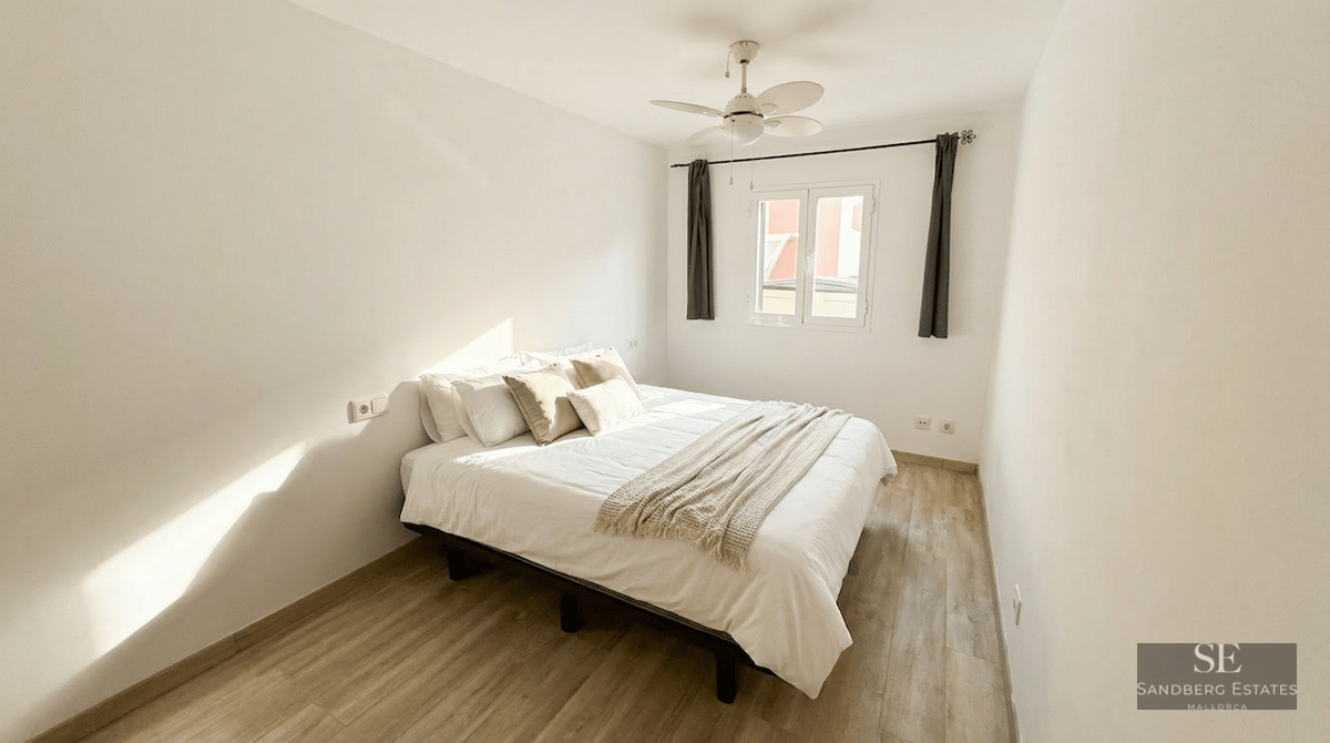 Bright bedroom featuring a white bed, light wood flooring, a white ceiling fan, and natural light.