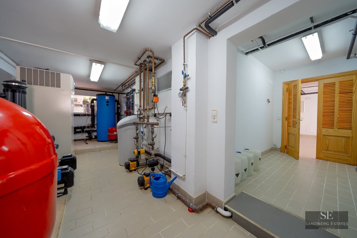 Technical room with water tanks, pumps, and copper piping on white tiled floors.