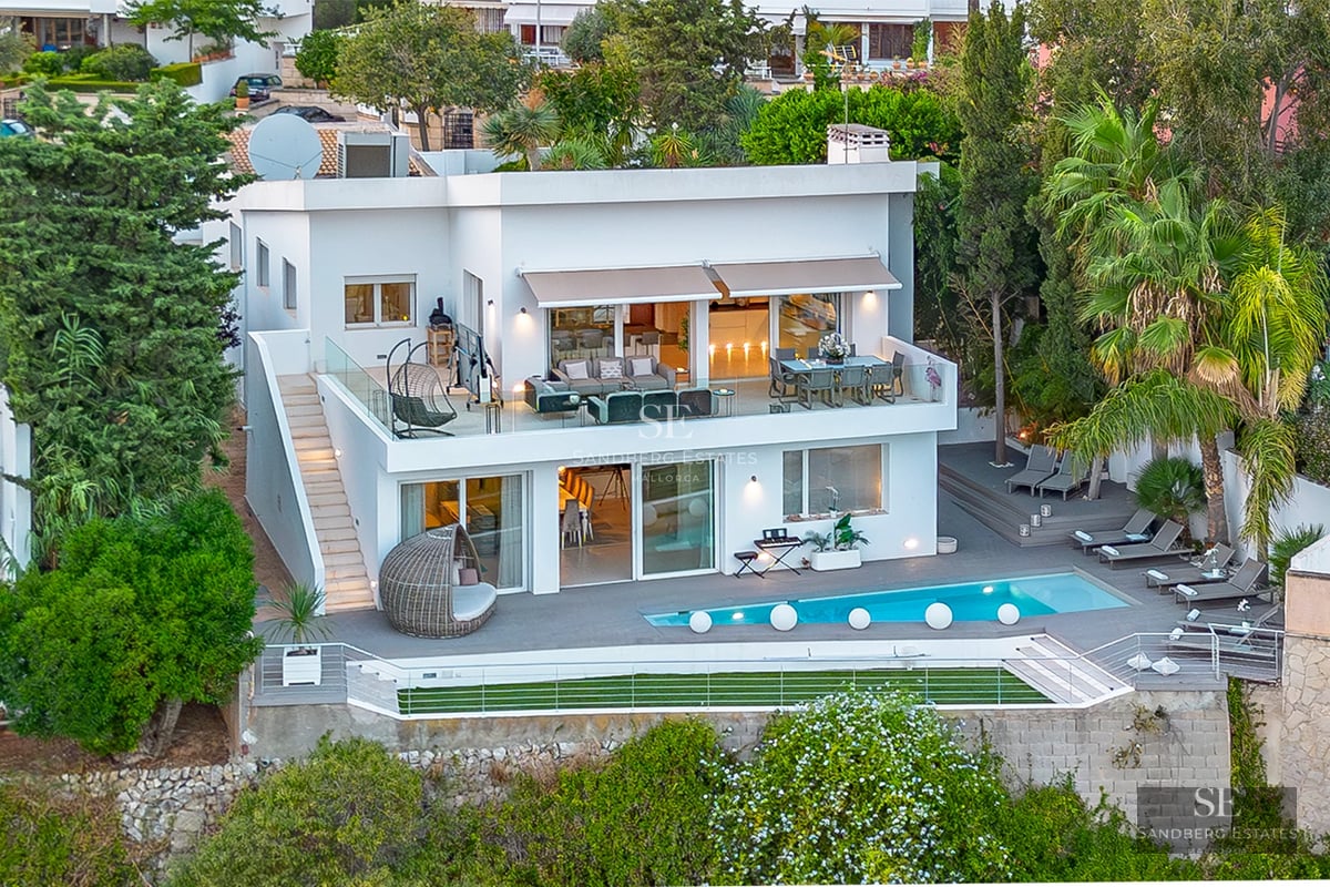 Exterior view of a modern villa featuring a pool, manicured garden, and spacious terraces. Sleek architectural design with warm lighting.