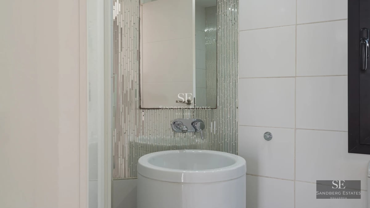 View of infinity pool with sun loungers, manicured garden, and modern architecture. Luxury and comfort in a tranquil setting.