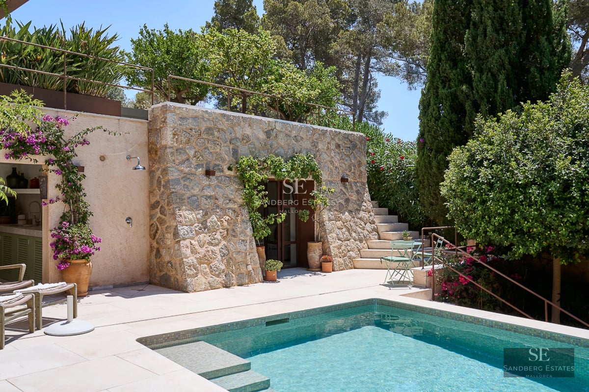 Spacious living room with floor-to-ceiling windows, natural light, light wood floors, and modern designer furniture. Elegant and comfortable.