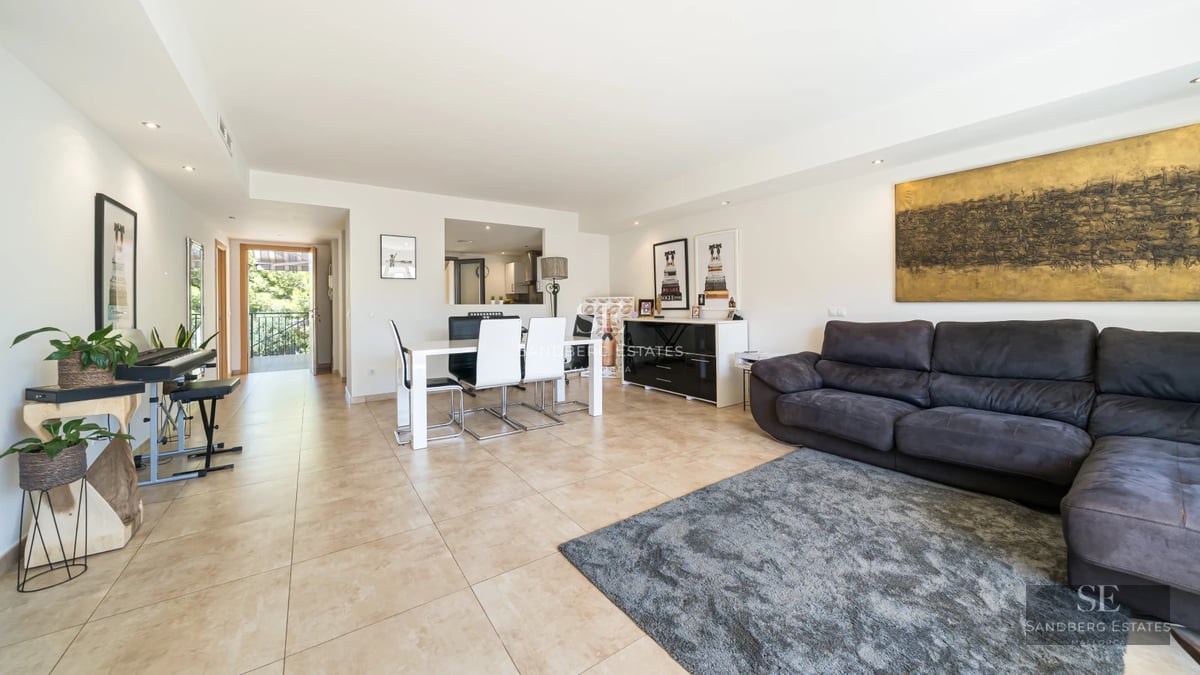 View of a reflecting pool surrounded by lawn and a modern house with large windows and a glass balcony.