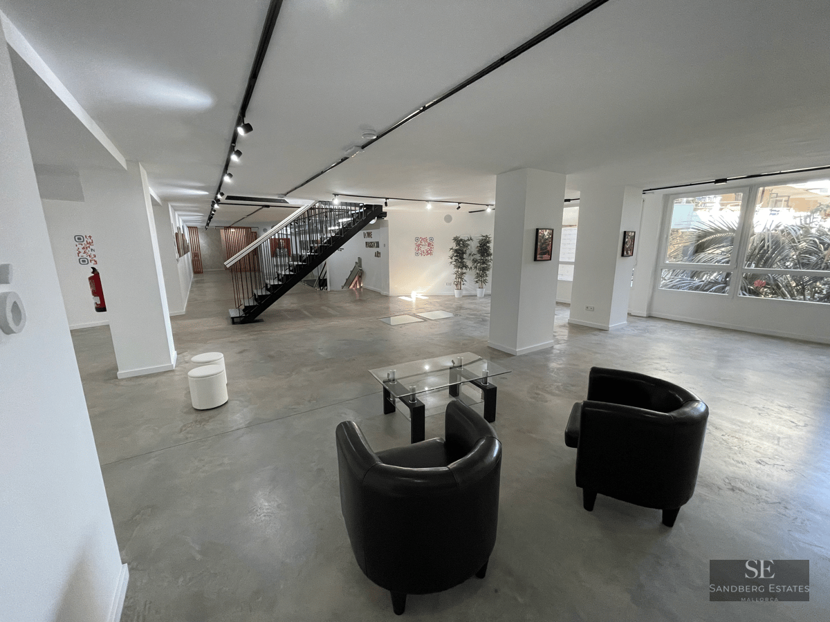 Spacious area with polished concrete floors, black leather armchairs, and a minimalist metal staircase.