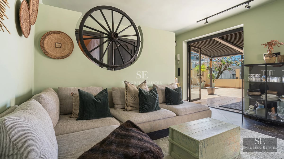 Spacious living room with floor-to-ceiling windows, light wood floors, modern furniture, and access to a terrace overlooking the pool and garden.