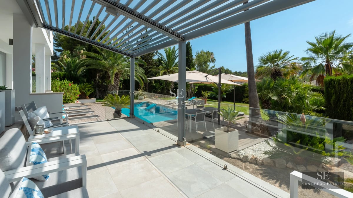 Spacious living room with modern fireplace, large windows, light wood floors, and minimalist decor. Abundance of natural light.