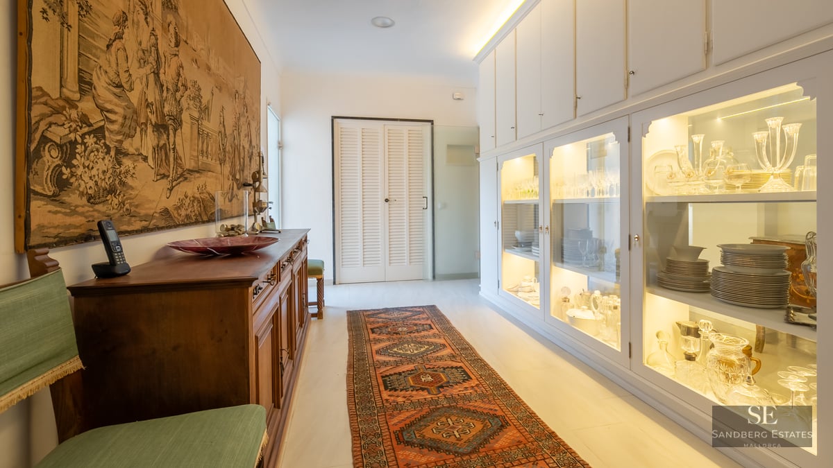 Hallway featuring a large historical tapestry, an oriental runner rug, and illuminated white glass display cabinets.