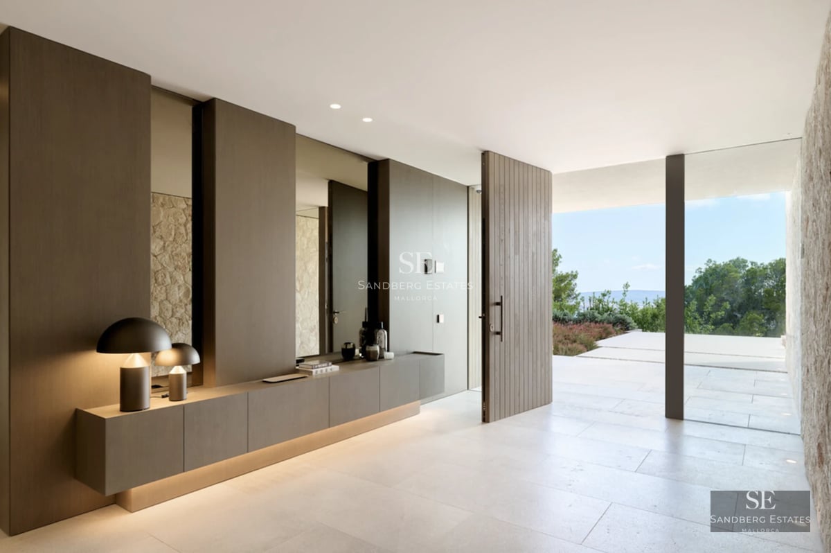 View of an infinity pool with sparkling blue water. Modern architecture, surrounded by lush vegetation. Clear sky.