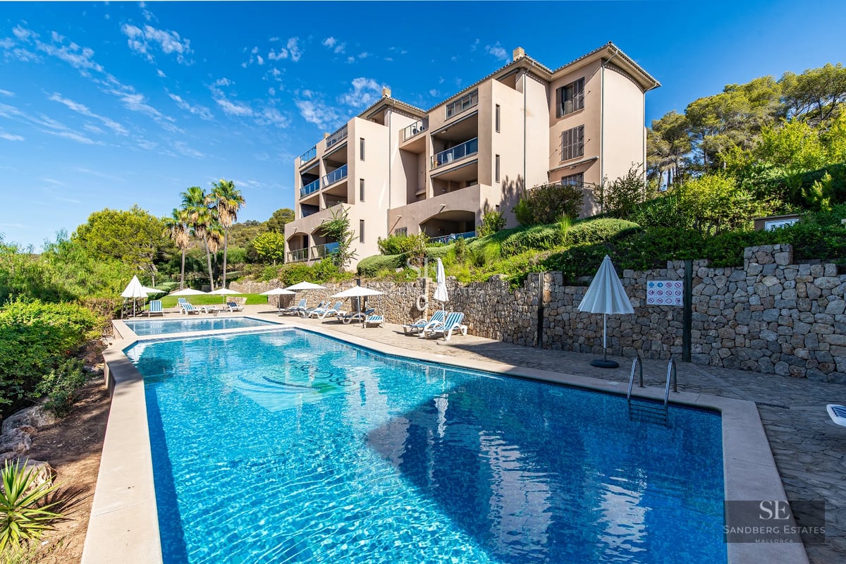 Aerial view of luxurious house with turquoise pool, garden, and terrace. Modern architecture with large windows.