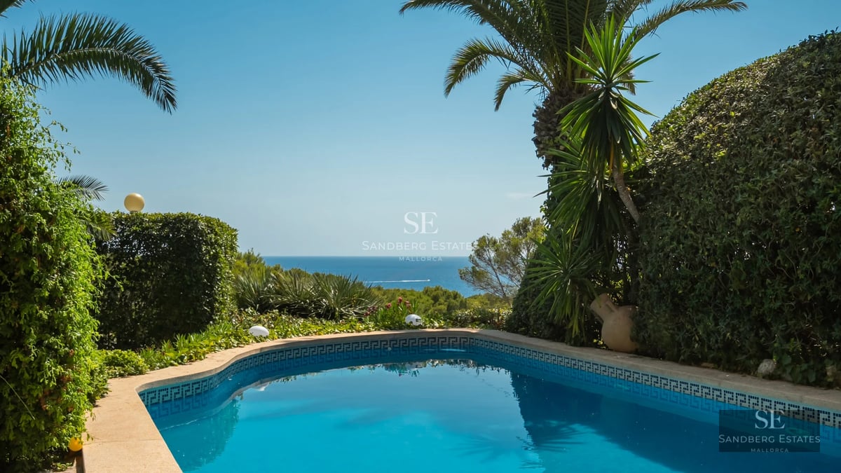 Balcony with glass railing and panoramic sea view. Modern furniture, soft lighting, and elegant design.