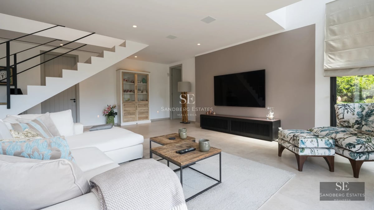 Spacious, bright living room featuring large windows and access to a balcony with panoramic sea views. Modern furniture in neutral tones.