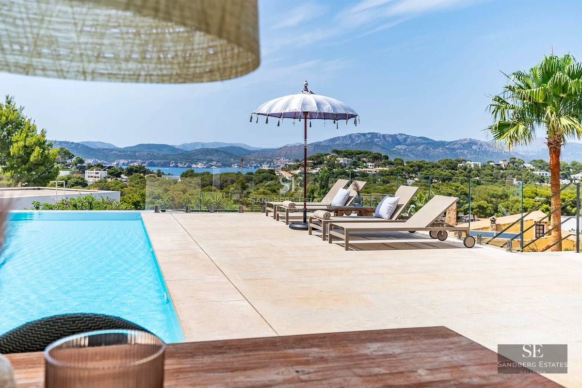 View of a luxurious modern villa with infinity pool, expansive terraces, and panoramic sea views. Minimalist and elegant design.