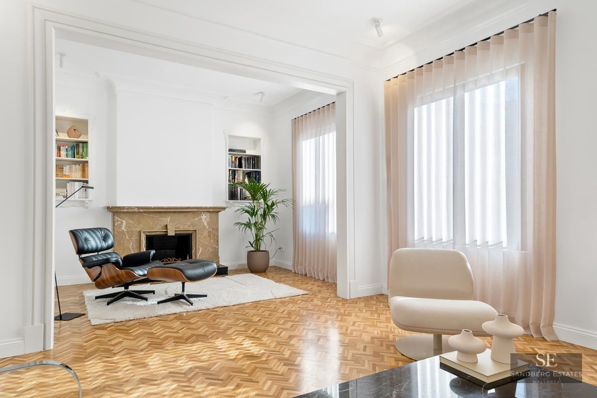 Bright living room with herringbone floors, a marble fireplace, and an Eames chair.