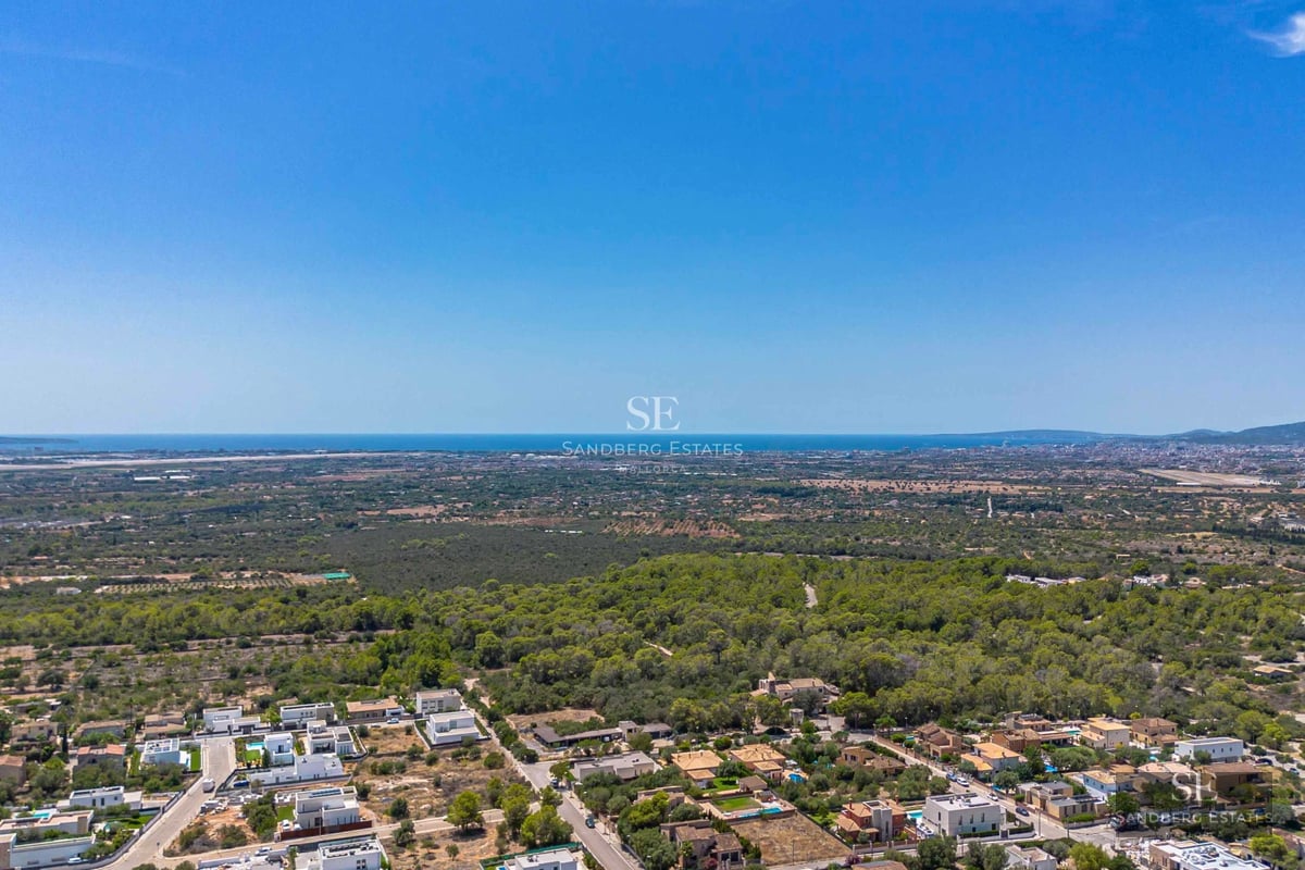 Spacious living room with large windows, sea view, light wood floors, and modern furniture in neutral tones.