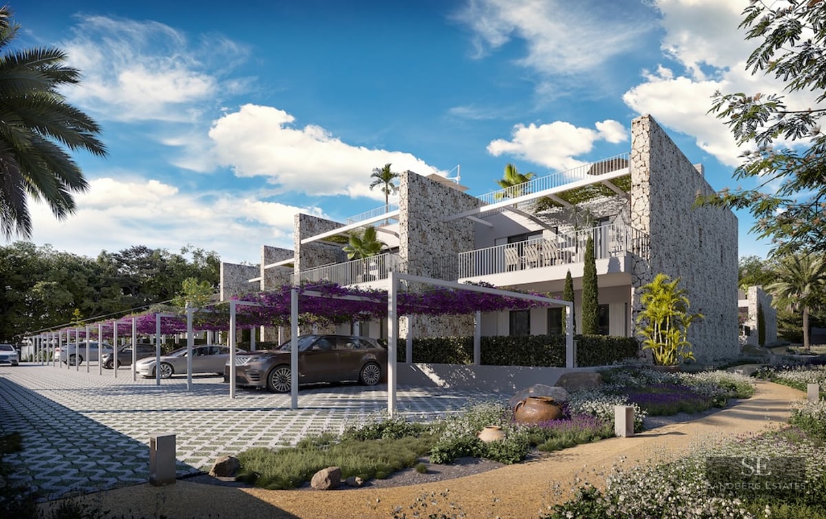 Luxury stone building with white pergolas covered in purple flowers over a modern parking area and garden path.