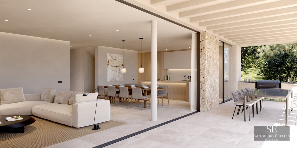 Spacious indoor living room with white sofa flowing into an outdoor terrace with dining and kitchen areas.