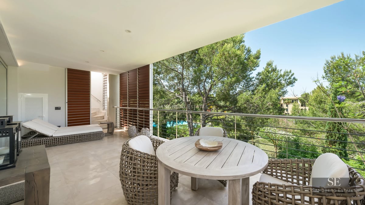 Aerial view of a luxurious villa with infinity pool, surrounded by greenery. Modern architecture with large terraces and windows.