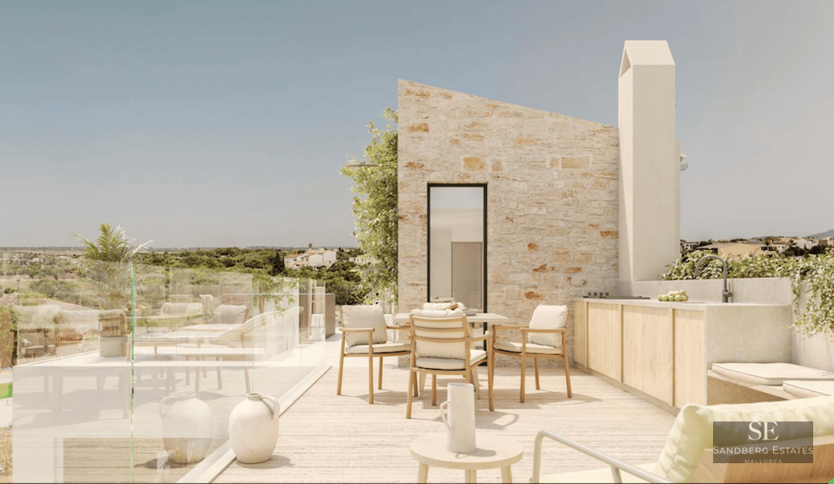 Modern stone terrace featuring a dining area, outdoor kitchen, and glass railing overlooking a scenic landscape.