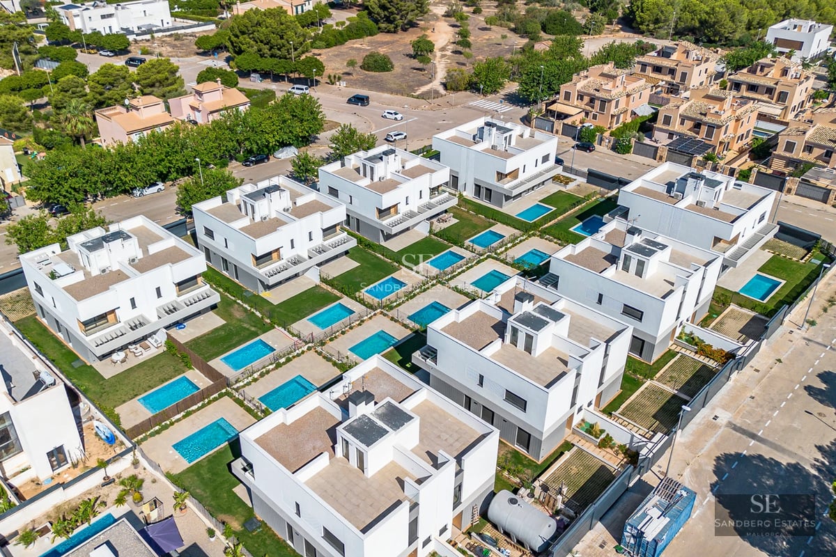 Exterior of modern villa with reflecting pool, minimalist design, and large windows. Green landscape and blue sky.
