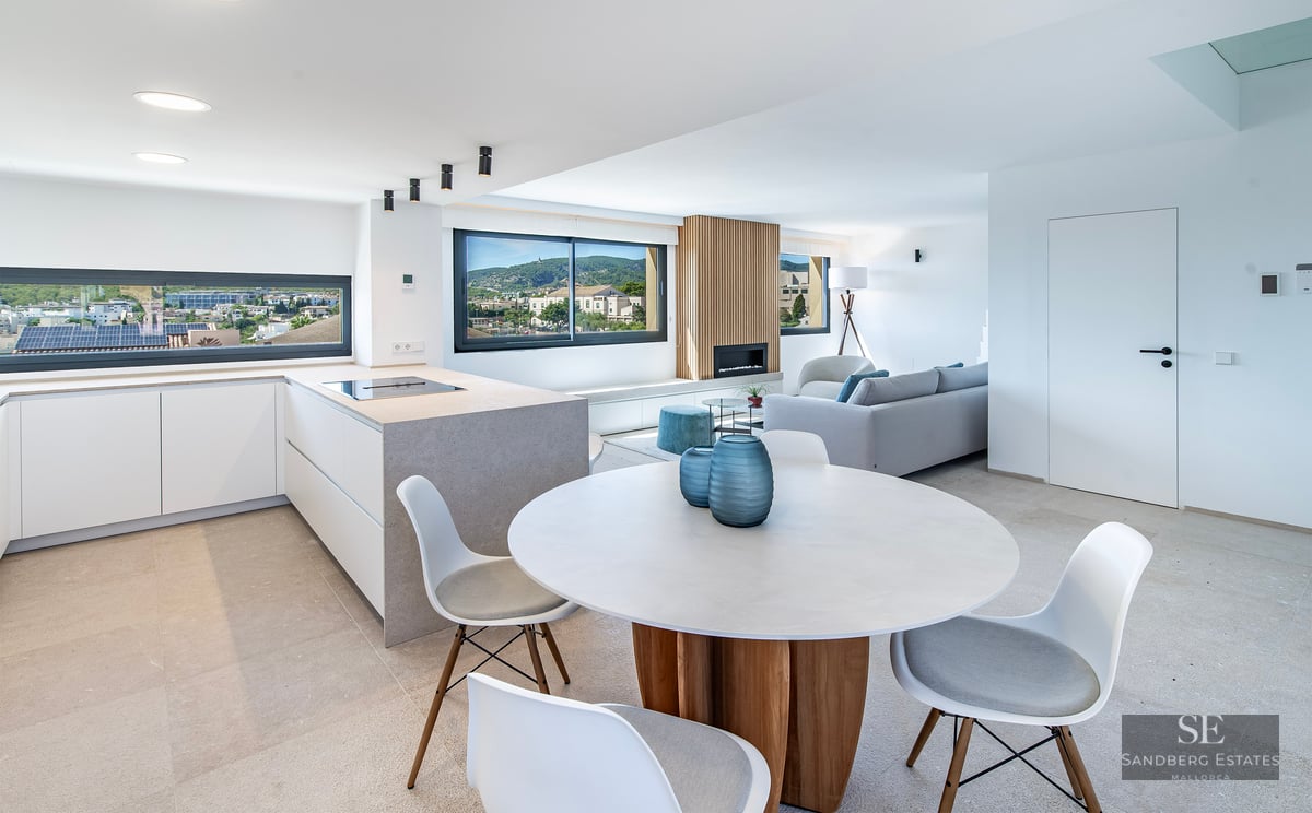 Bright open-plan interior featuring a dining area, modern kitchen island, and living room with scenic town views.